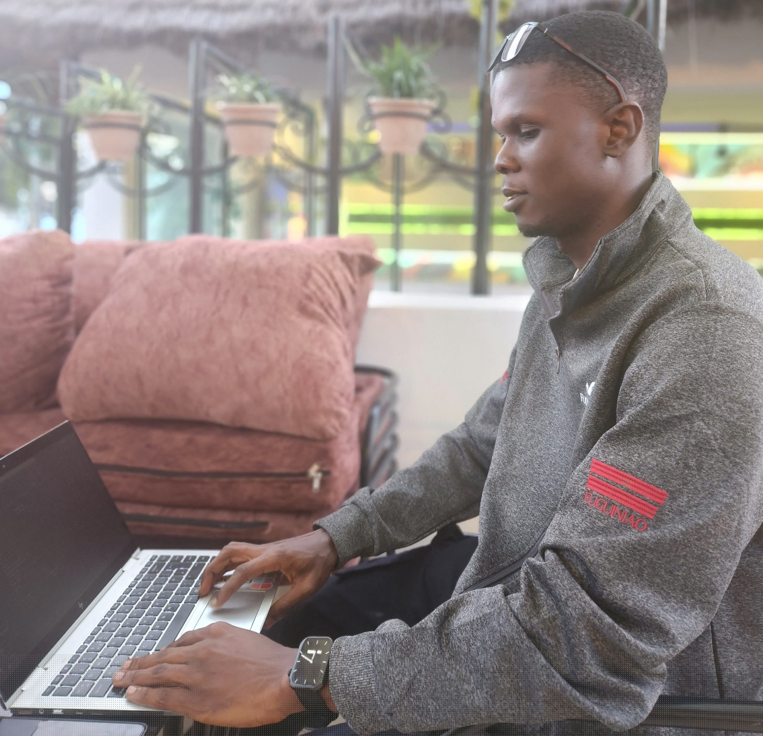 Ayowande working on a laptop at an outdoor cafe